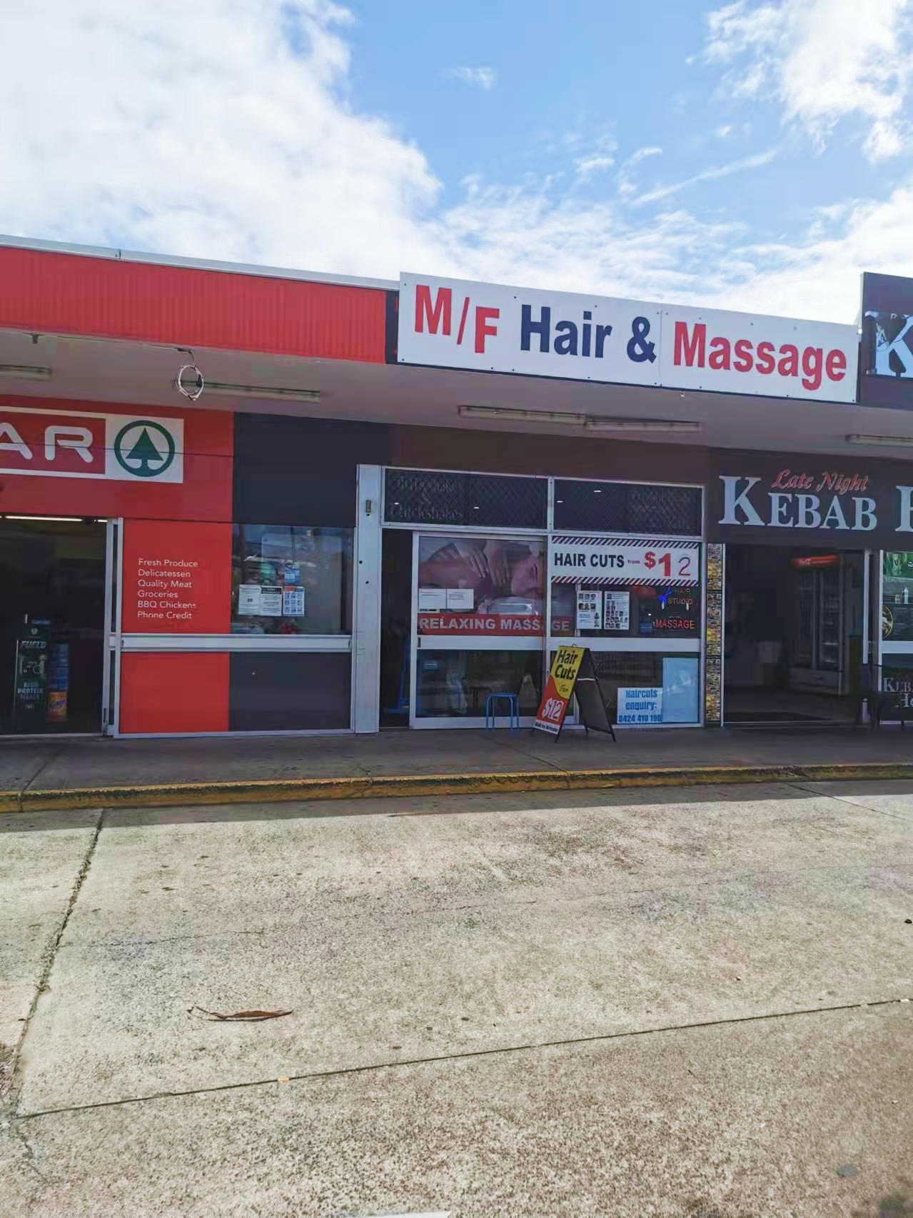 The M/F Hair & Massage shopfront on Morayfield Road, with its red and navy sign and $12 haircuts in the window